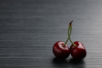 Photo of Fresh sweet cherries on dark wooden table, space for text