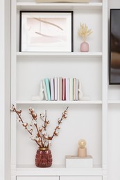 Shelves with different decor and fluffy cotton flowers indoors. Interior design