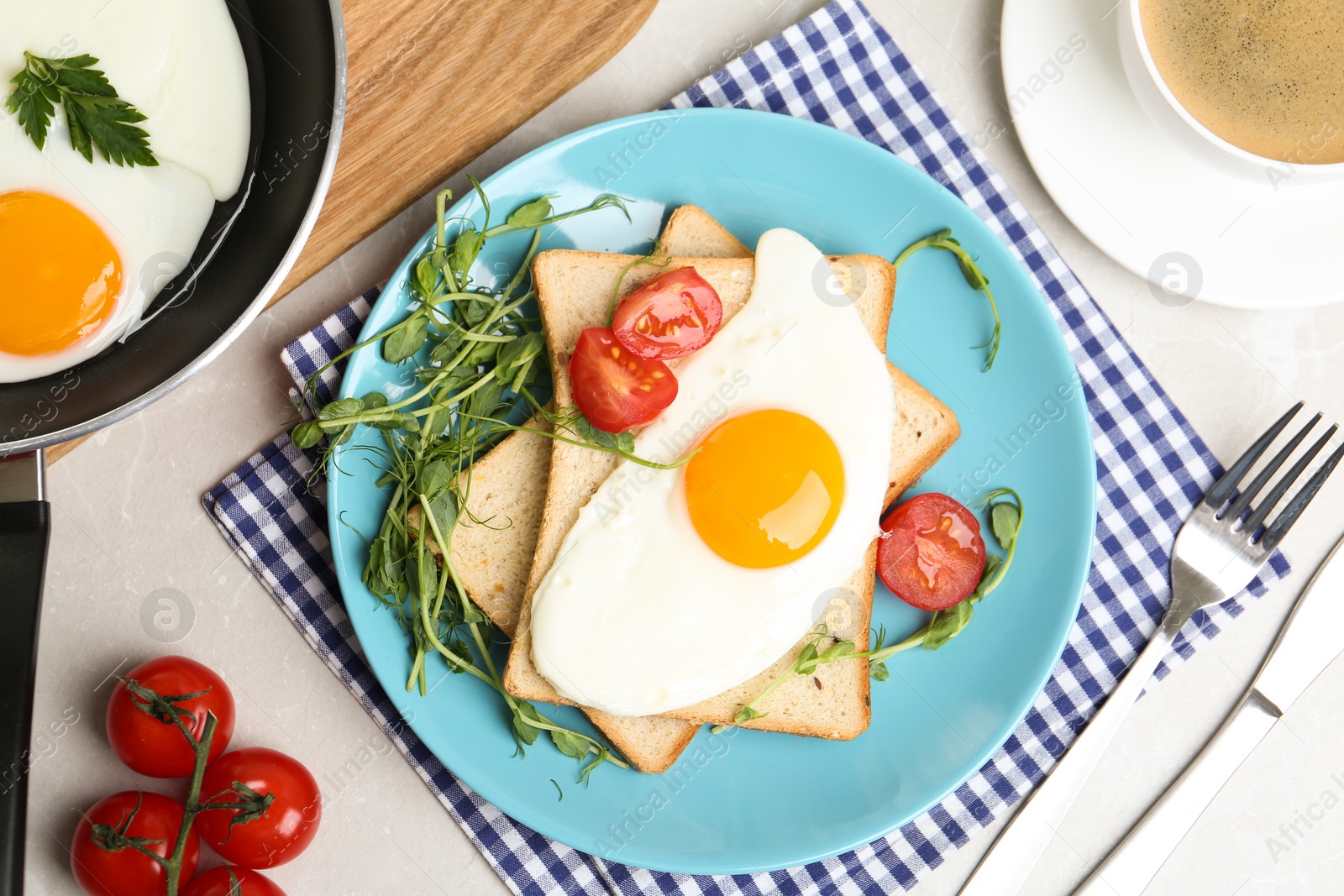 Photo of Tasty fried egg with bread and garnish on light grey table, flat lay