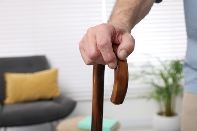 Photo of Senior man with walking cane at home, closeup. Space for text