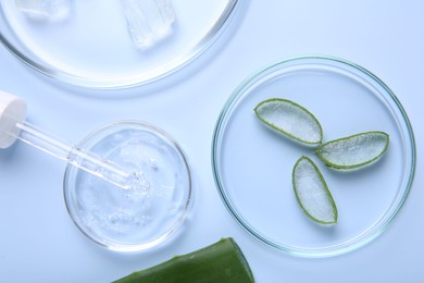 Photo of Flat lay composition with cut aloe vera and cosmetic gel on light blue background