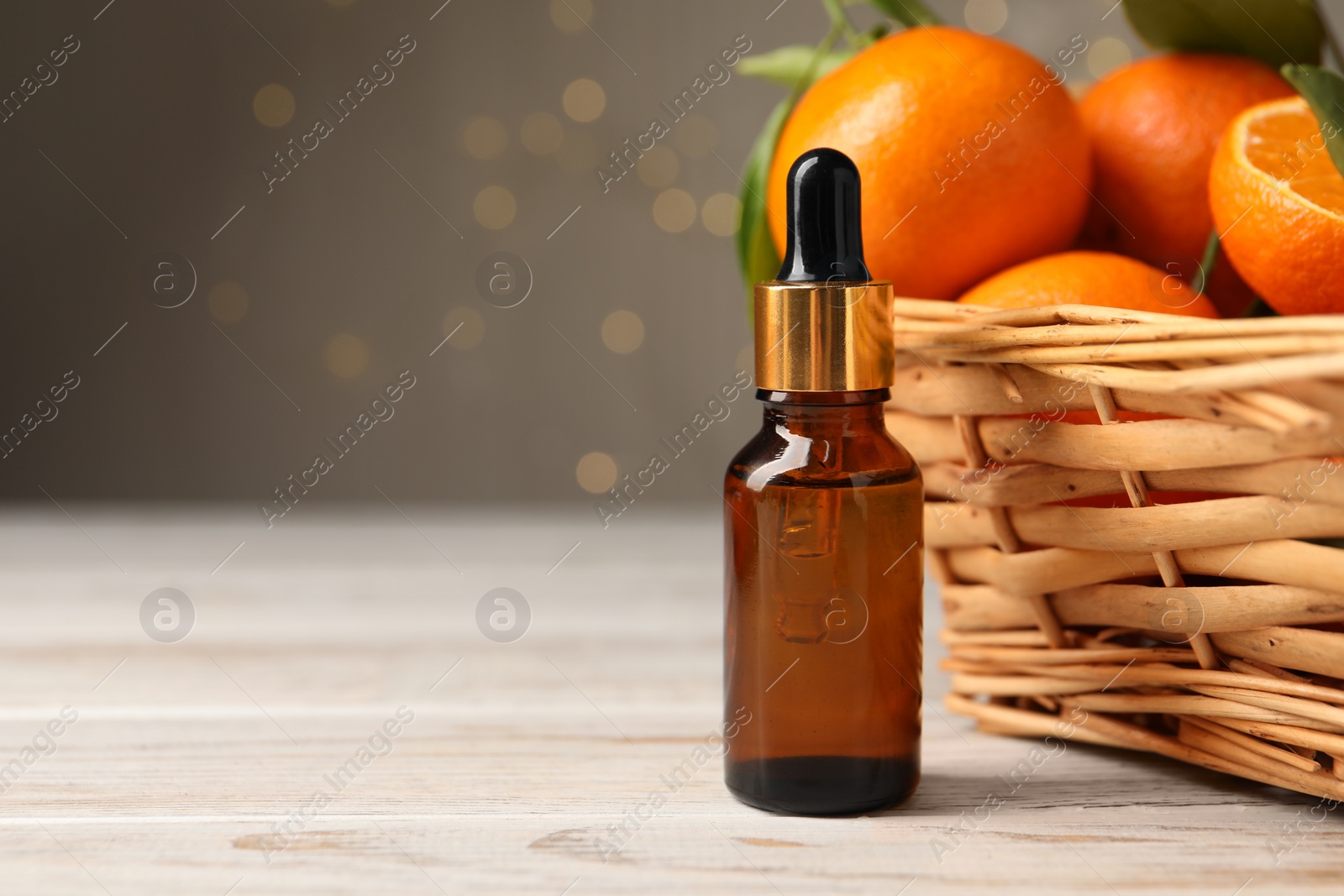 Photo of Bottle of tangerine essential oil and fresh fruits on white wooden table. Space for text