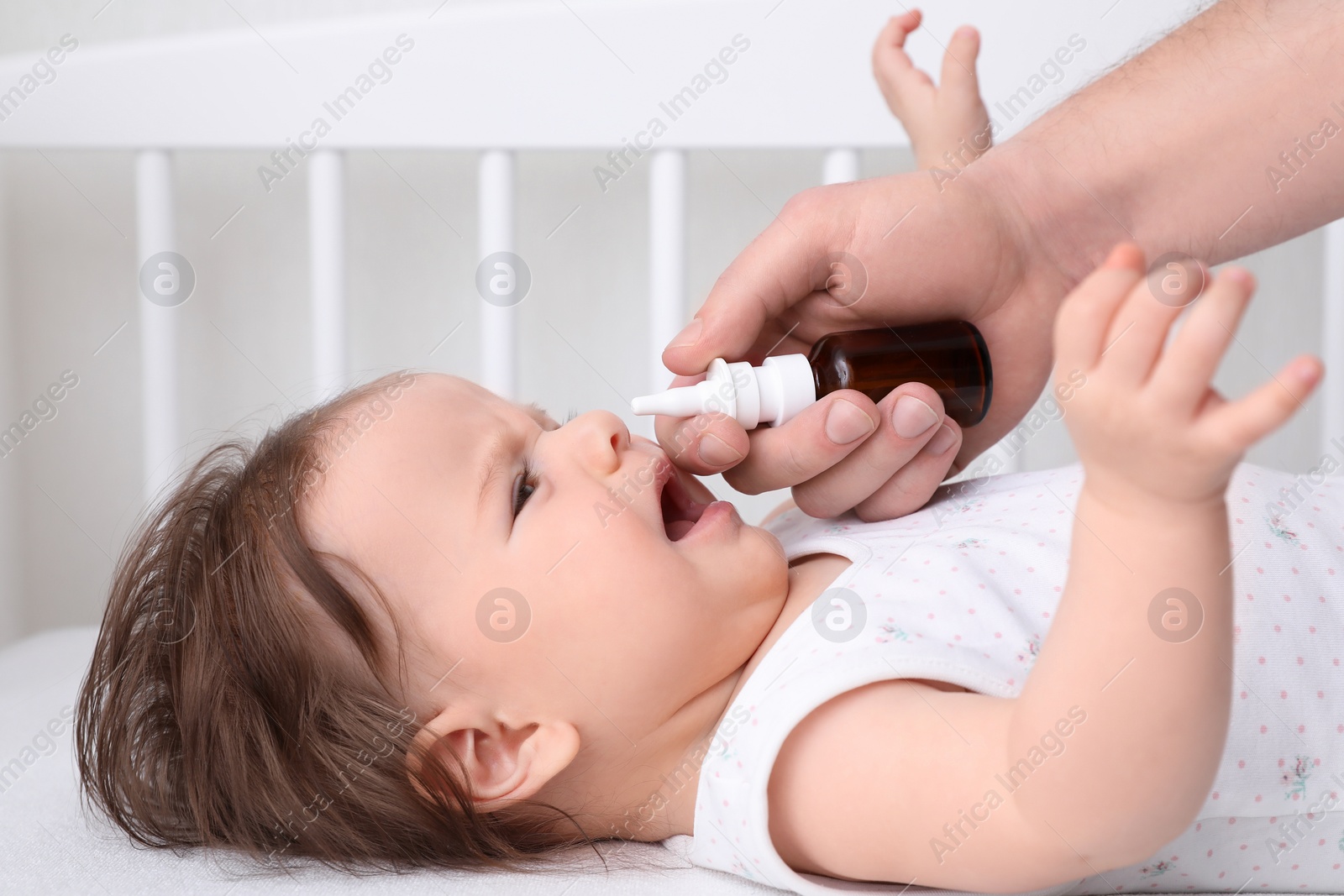 Photo of Father taking care of little baby suffering from runny nose in bed, closeup