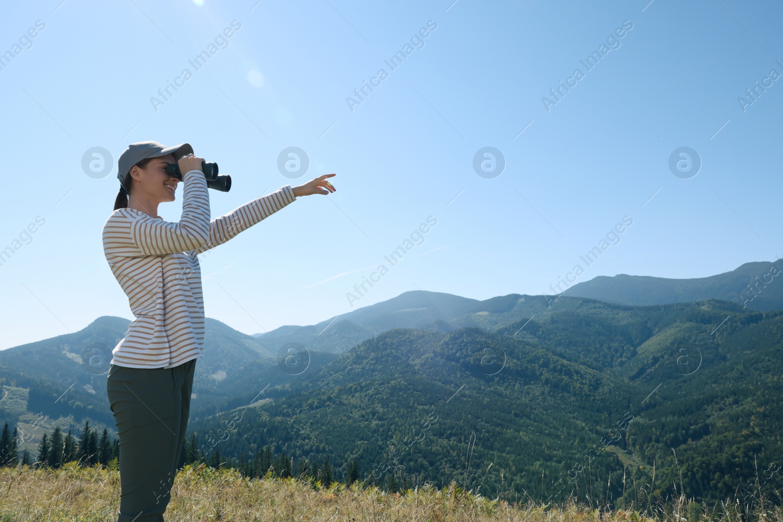 Photo of Woman looking through binoculars in mountains on sunny day