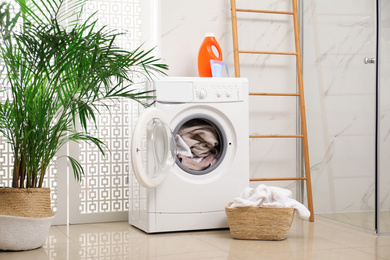 Modern washing machine with towels in bathroom