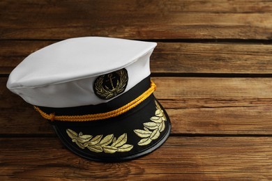 Photo of Peaked cap with accessories on wooden background, space for text