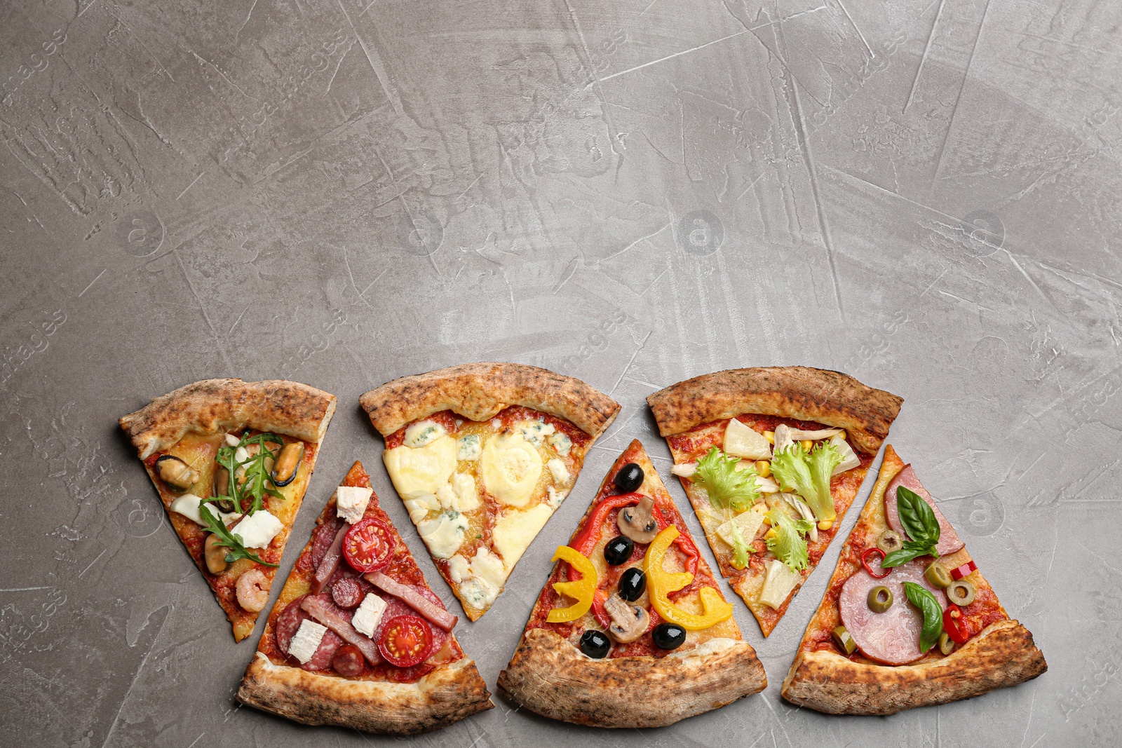 Photo of Slices of different delicious pizzas on grey table, flat lay. Space for text