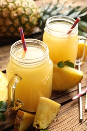 Photo of Delicious pineapple juice and fresh fruit on wooden table, closeup