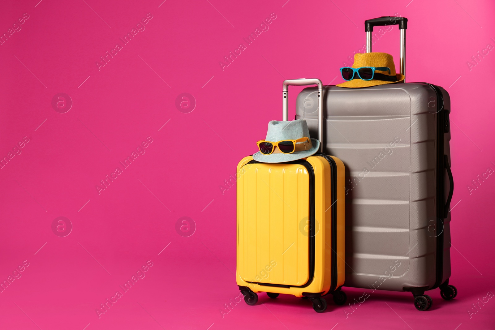 Photo of Stylish suitcases with hats and sunglasses on color background. Space for text