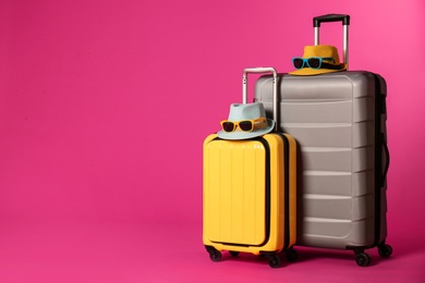 Stylish suitcases with hats and sunglasses on color background. Space for text