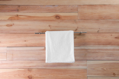 Photo of Rack with clean soft towel on wooden wall