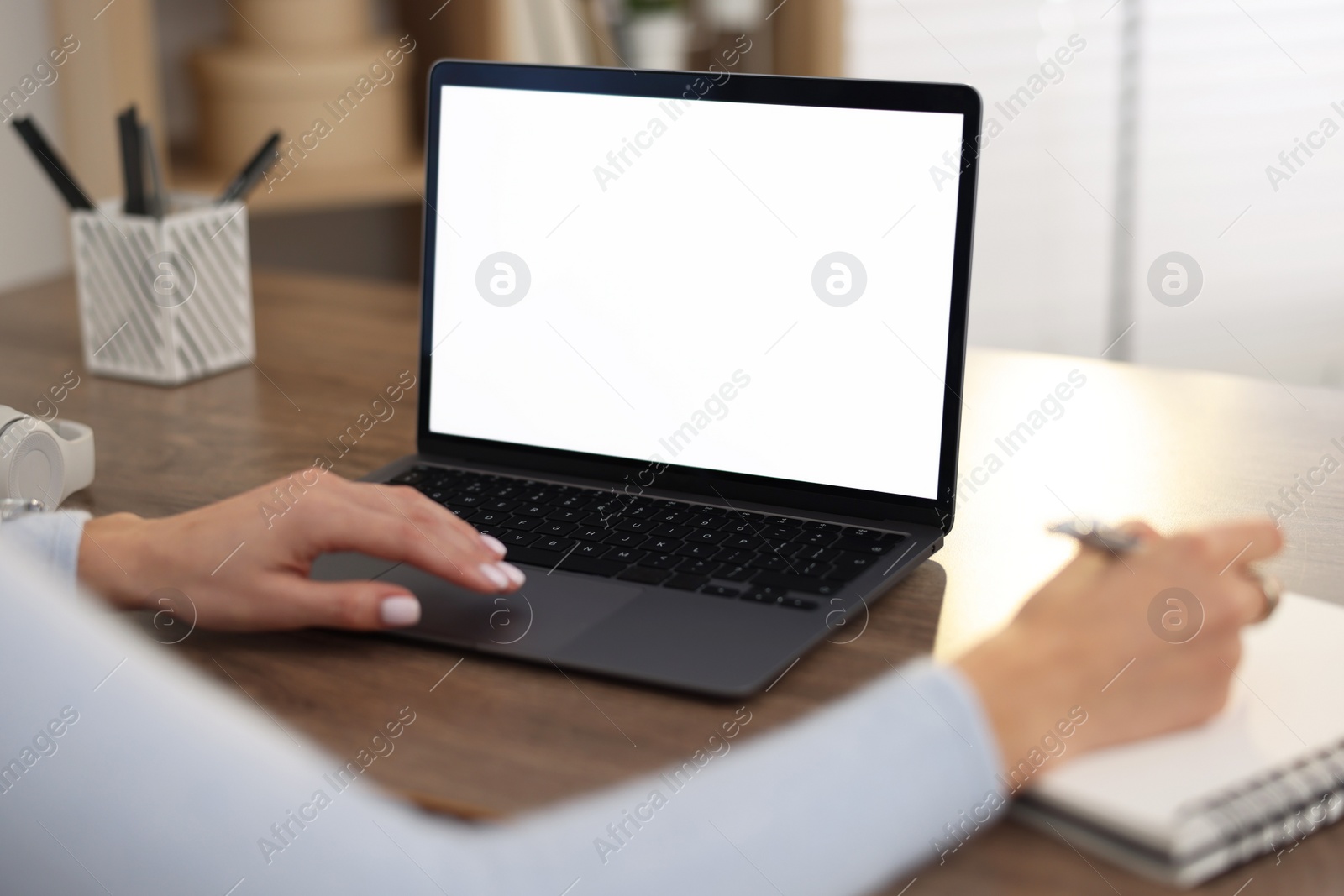 Photo of Young woman writing down notes during webinar at table indoors, closeup