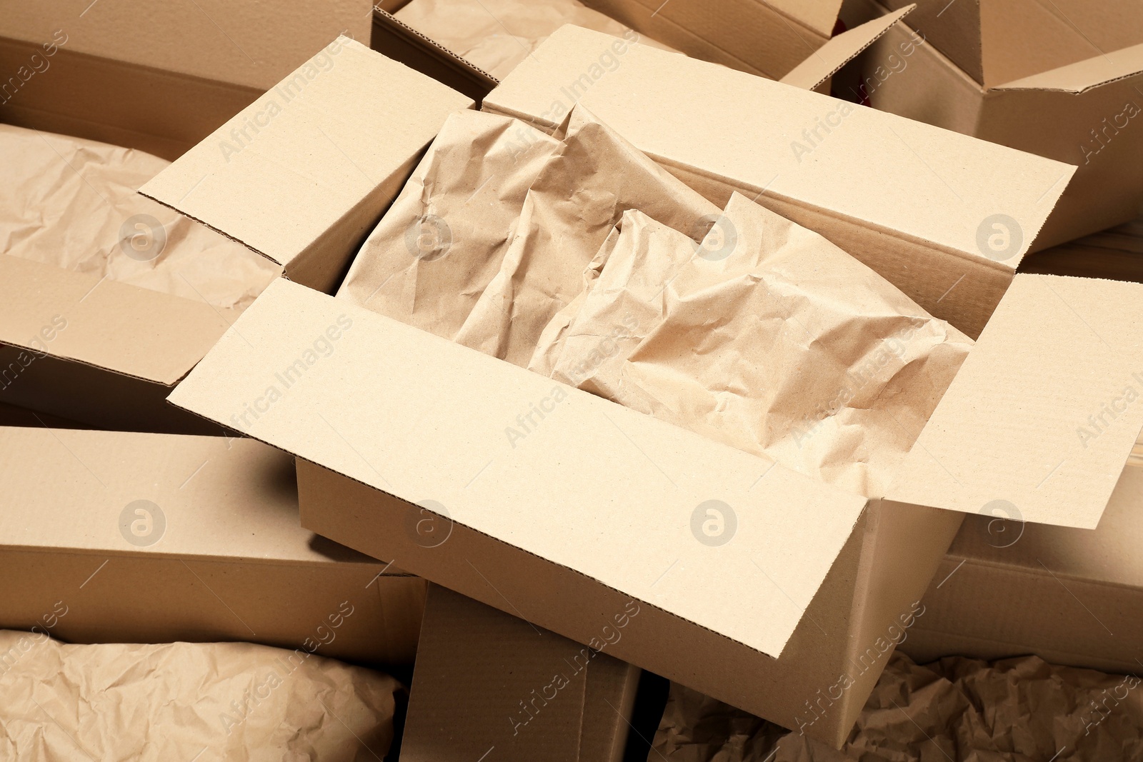 Photo of Many open cardboard boxes with crumpled paper as background