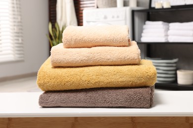 Photo of Stack of clean towels on white table in laundry room