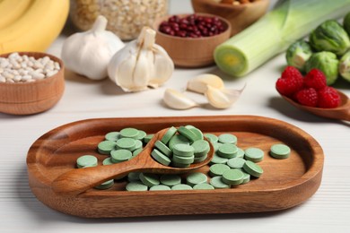 Many prebiotic pills and food on white wooden table