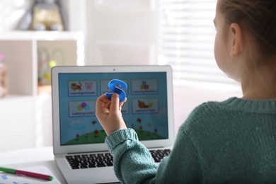 Photo of Little girl learning English indoors at online lesson, closeup