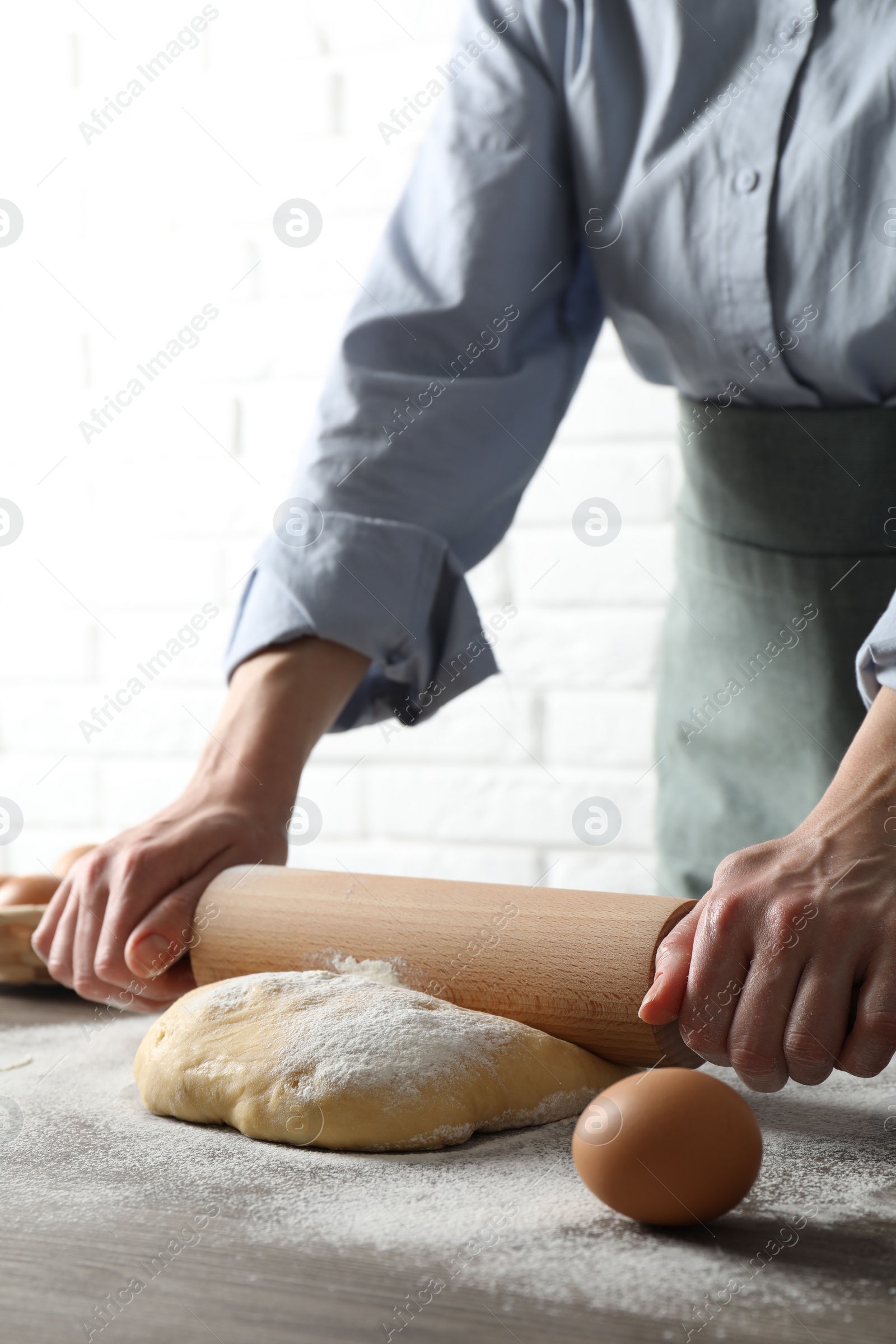 Photo of Woman rolling raw dough at table, closeup