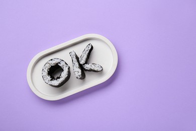 Photo of Word Ok made of sushi rolls on violet background, top view. Space for text