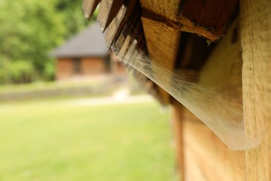 Photo of Cobweb on wooden building outdoors, closeup. Space for text