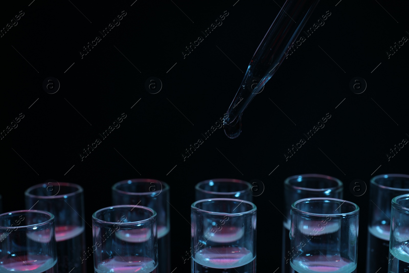 Photo of Dripping reagent into test tube on black background, closeup. Laboratory analysis