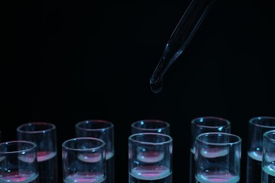 Photo of Dripping reagent into test tube on black background, closeup. Laboratory analysis