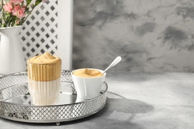 Photo of Glass of delicious dalgona coffee and cream on light grey table, space for text