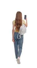 Young woman in casual outfit using smartphone while walking on white background, back view