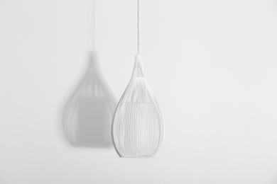 Photo of Modern lamp hanging on white background. Idea for interior design