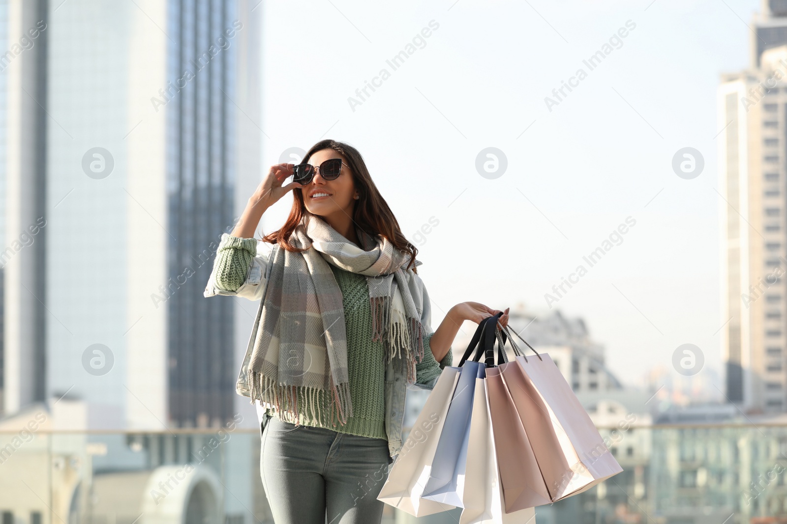 Photo of Beautiful young woman with shopping bags on city street