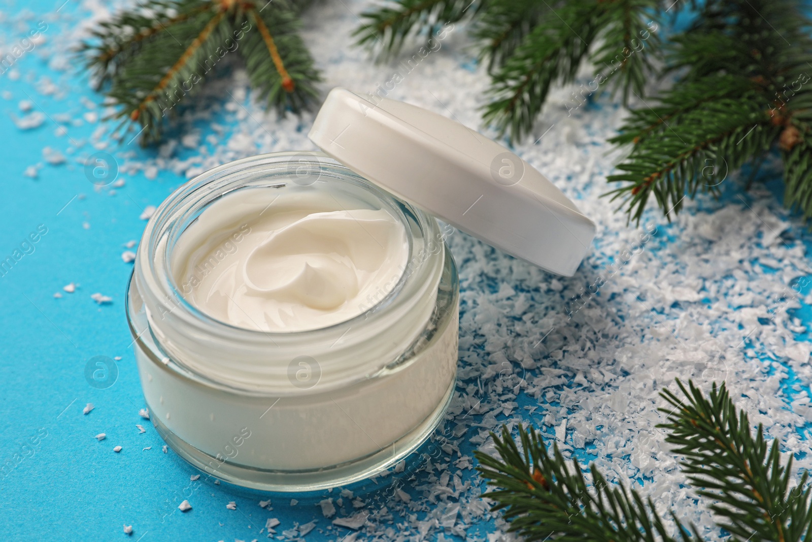 Photo of Jar of hand cream and Christmas decor on light blue background. Winter skin care