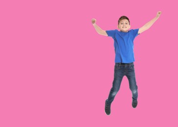 Happy boy jumping on pink background, space for text