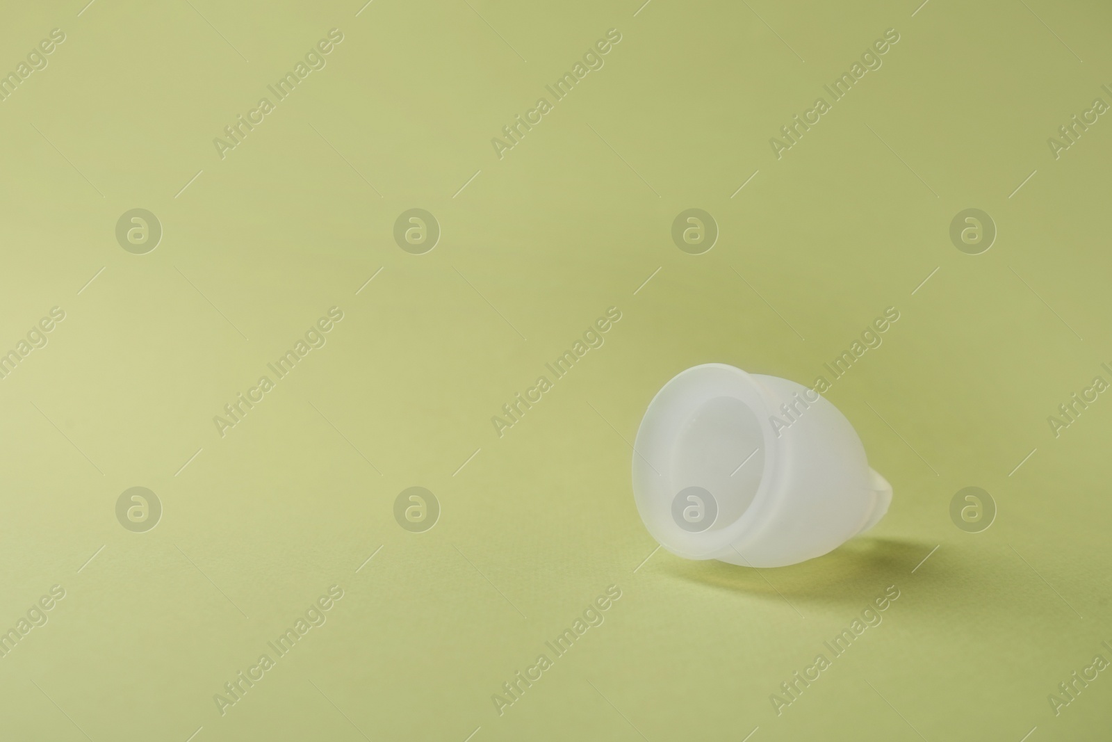 Photo of Menstrual cup on green background. Space for text
