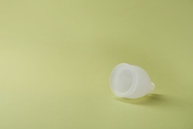 Photo of Menstrual cup on green background. Space for text