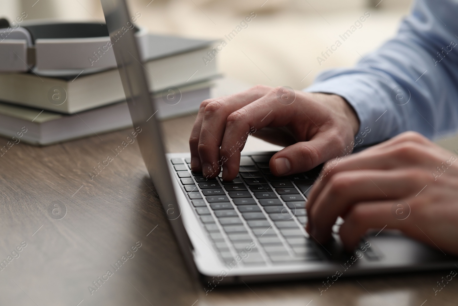 Photo of E-learning. Man using laptop during online lesson at table indoors, closeup