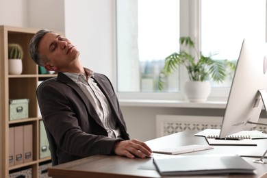 Photo of Man snoozing at wooden table in office