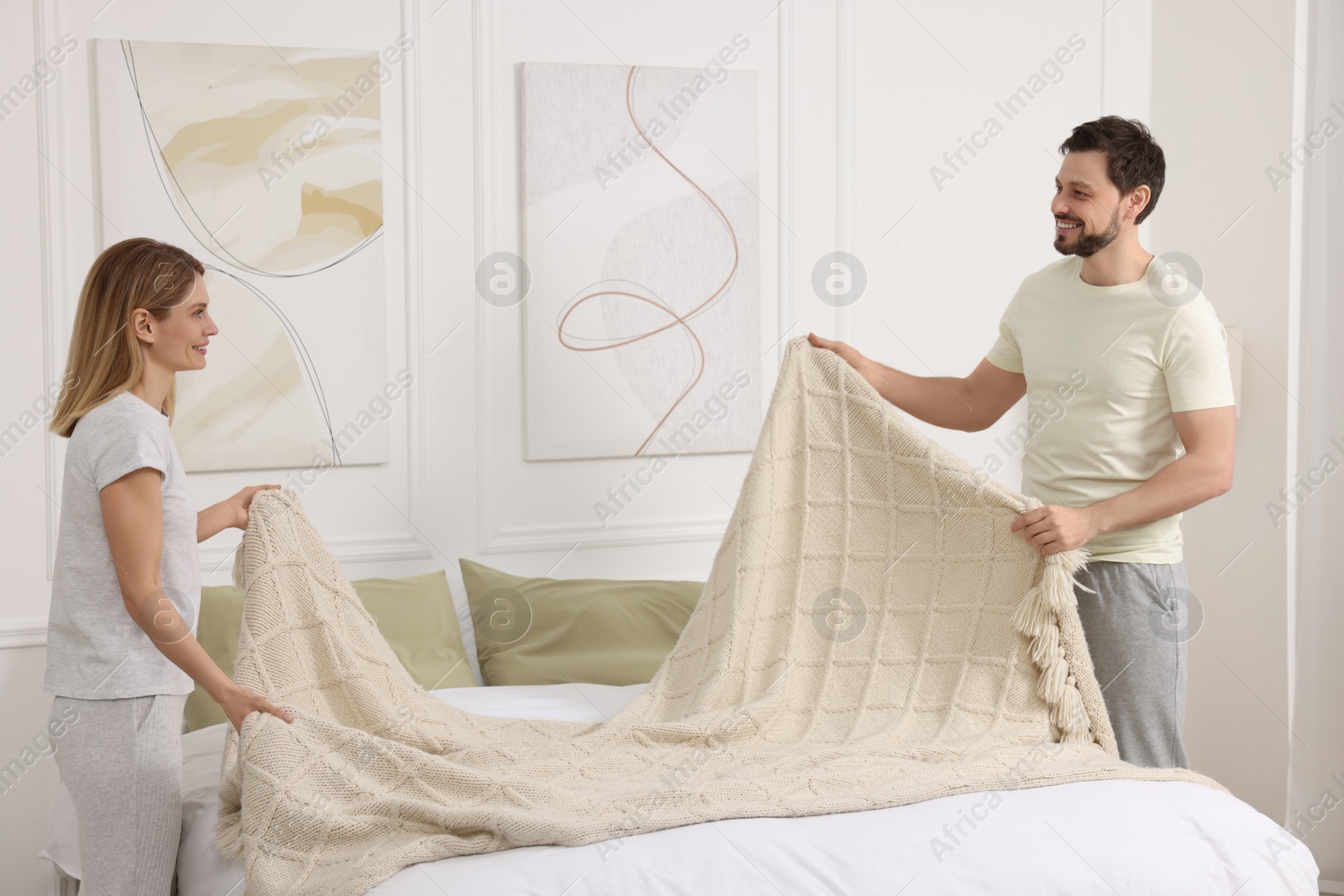 Photo of Couple changing bed linens at home. Domestic chores