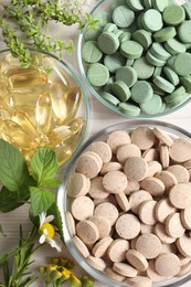 Photo of Different pills, flowers and herbs on white table, flat lay. Dietary supplements