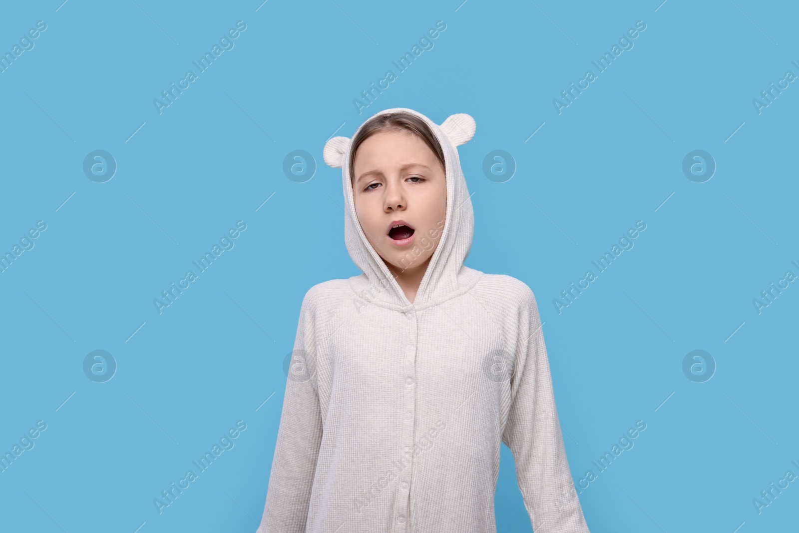 Photo of Sleepy girl yawning on light blue background. Insomnia problem