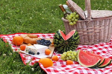 Picnic blanket with delicious food and wine outdoors on summer day