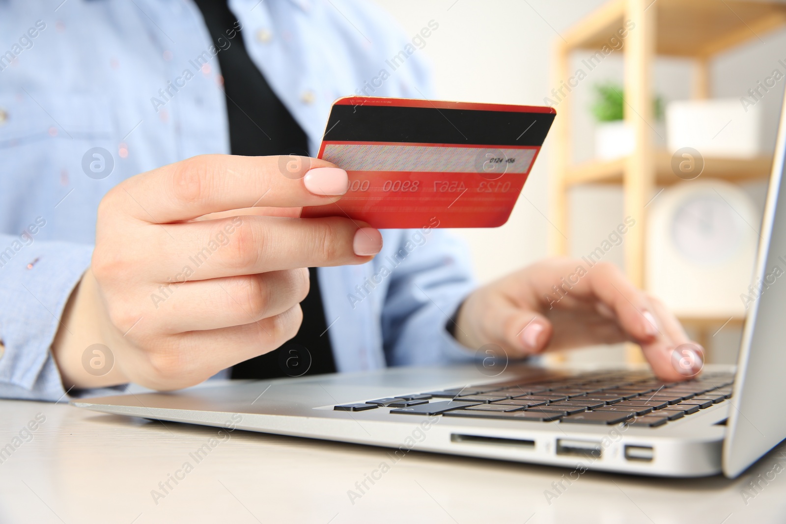 Photo of Online payment. Woman with credit card using laptop at white table indoors, closeup