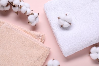 Photo of Cotton branch with fluffy flowers and terry towels on beige background, flat lay