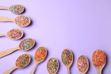 Photo of Colorful sprinkles in spoons on lilac background, flat lay with space for text. Confectionery decor