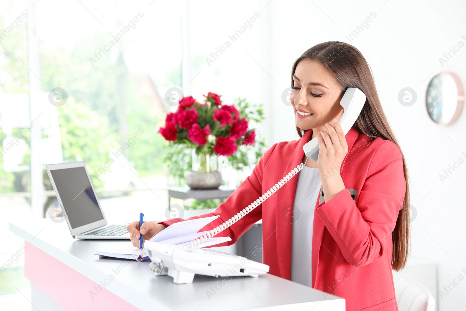 Photo of Beauty salon receptionist talking on phone at desk