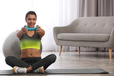 Photo of Young woman in fitness clothes doing exercise with dumbbell at home. Space for text