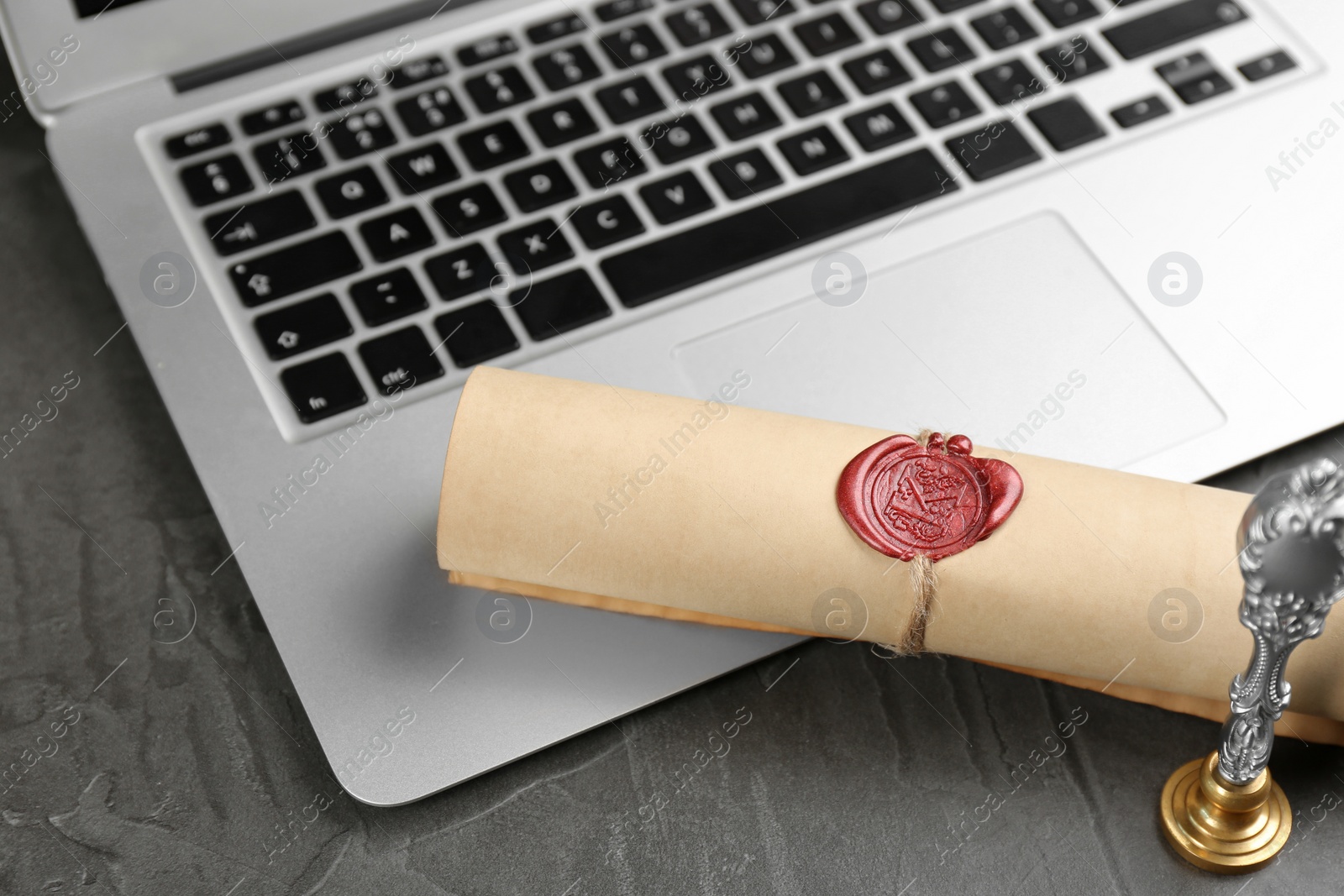 Photo of Notary's public pen and sealed document near laptop on grey stone table