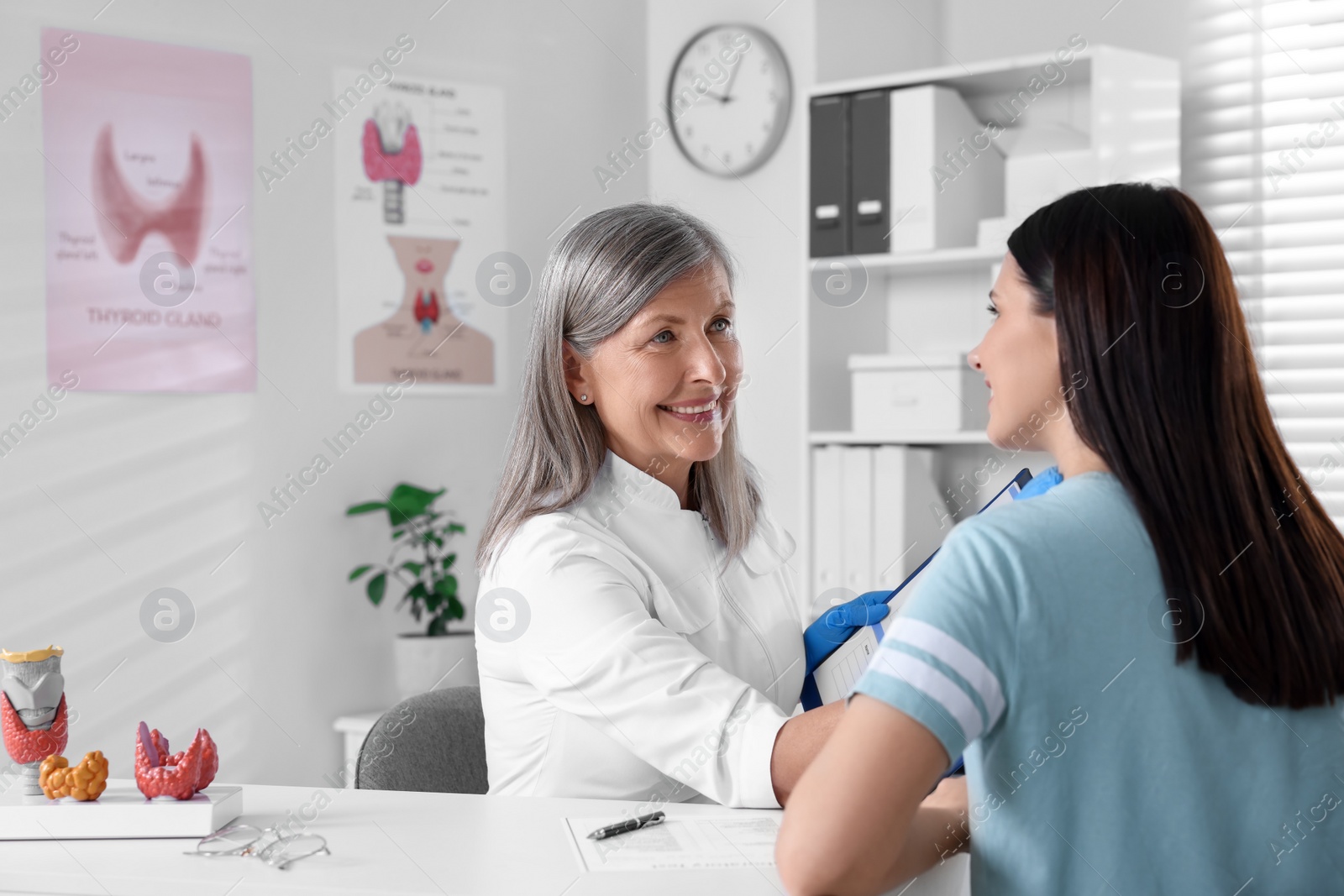 Photo of Endocrinologist examining thyroid gland of patient at table in hospital