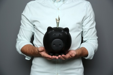 Photo of Young man with piggy bank on grey background, closeup