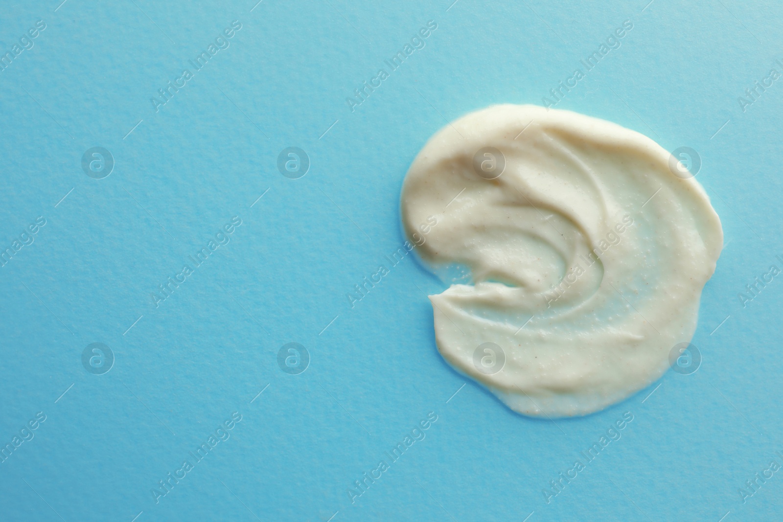 Photo of Sample facial cream on turquoise background, top view