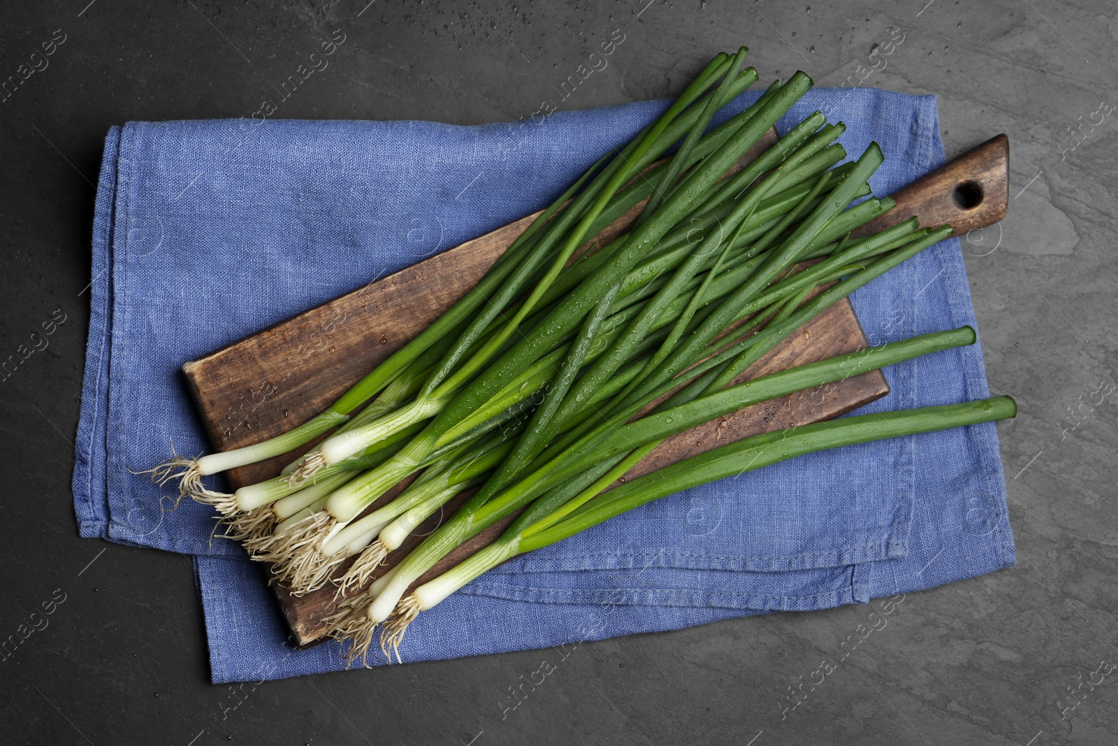 Photo of Fresh green spring onions on black table, flat lay