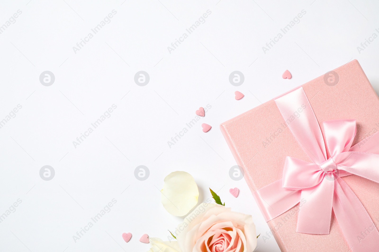 Photo of Pink gift box and beautiful flower on white background, flat lay. Space for text